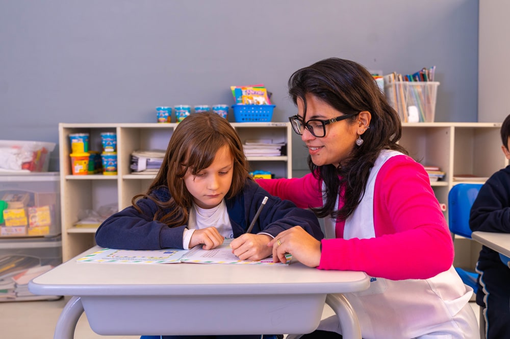 Foto: Professora auxiliando aluna em atividade