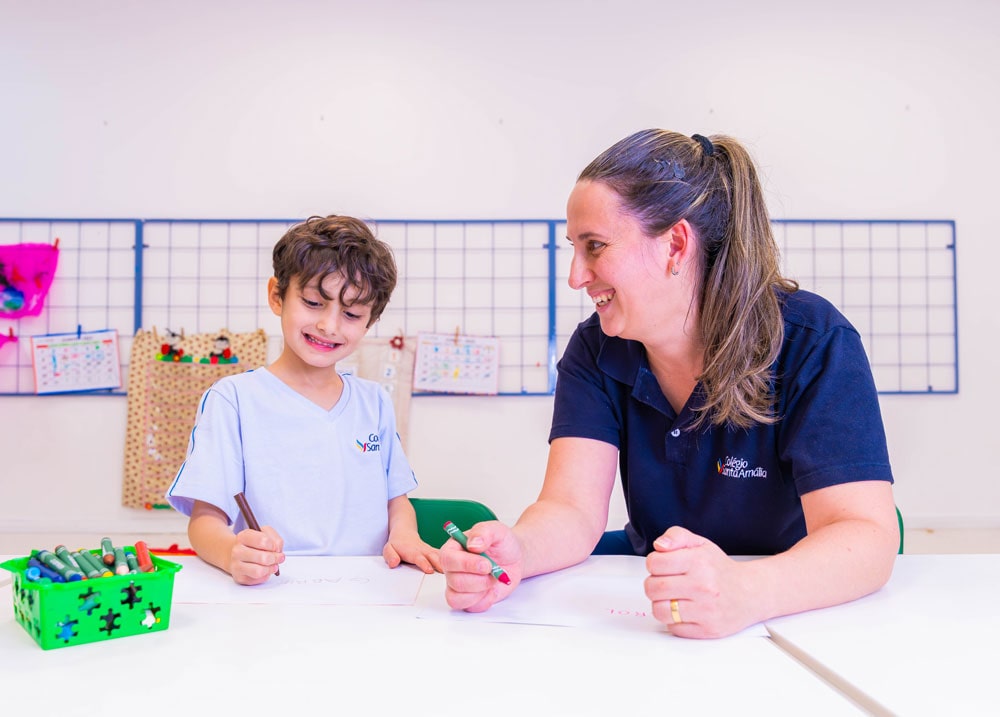 Foto: Professora auxiliando aluno em tarefa de artes